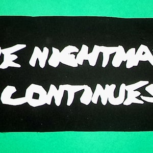May include: Black and white text on a black background reads "THE NIGHTMARE CONTINUES".
