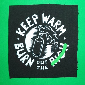 Peut inclure: Patch brodé noir et blanc avec le texte "Keep Warm. Burn Out The Right." Une image stylisée d'un flacon pulvérisateur se trouve au centre du patch.