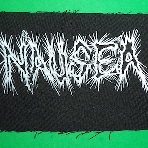 Könnte beinhalten: Weißer gestickter Aufnäher auf schwarzem Stoff mit dem Wort "NAUSEA" in einer stilisierten Schrift.