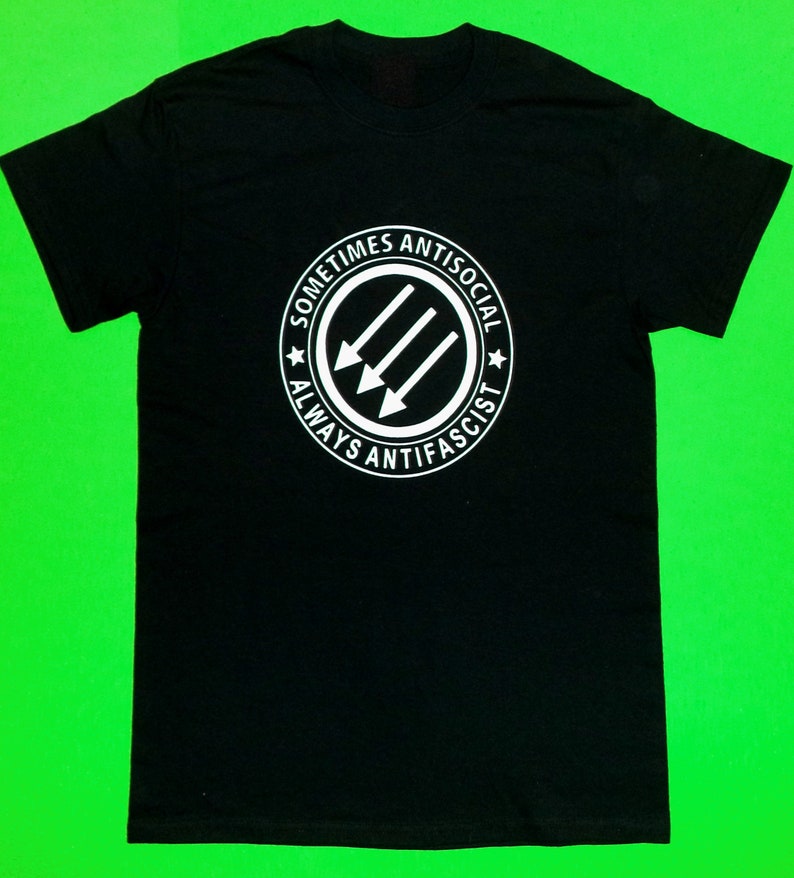 May include: Black t-shirt with a white circle graphic that says "Sometimes Antisocial Always Anti-Fascist" with three arrows pointing to the right.
