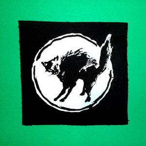 Peut inclure: Illustration en noir et blanc d'un chat à l'intérieur d'un cercle sur un fond carré noir. Le carré est sur un fond vert.