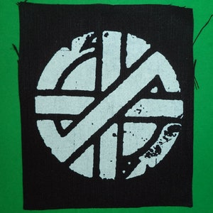 May include: Black and white embroidered patch with a circle design. The circle has a white background and black lines forming a geometric pattern.