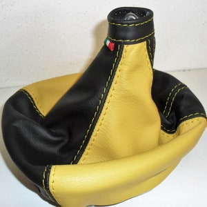 Puede incluir: Pomo de cambio de marchas de cuero negro y amarillo con costuras amarillas y una bandera italiana.