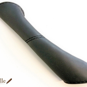 May include: Black leather pen holder with a curved shape and stitched seams.