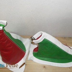 Op de afbeelding: Twee leren versnellingspookhoezen in rood, wit en groen, die lijken op de Italiaanse vlag. De hoezen liggen op een wit oppervlak.