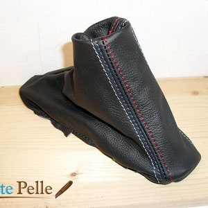 May include: Black leather gear shift boot with white, blue, and red stitching.