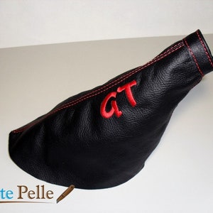May include: Black leather gear shift boot with red stitching and "GT" embroidered in red.