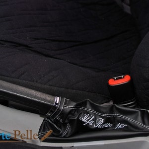 May include: Black leather car handbrake cover with white stitching and the text "Alfa Romeo 156" embroidered on it.