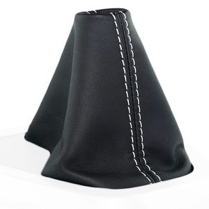 Op de afbeelding: Zwarte leren versnellingspookhoes met witte stiksels.