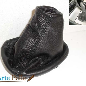 May include: Black leather gear shift boot cover. The cover is made of high-quality leather and has a stitched seam around the top edge.