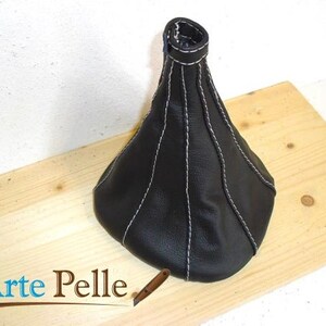 May include: Black leather gear shift boot with white stitching. The boot is cone-shaped and has a smooth surface.