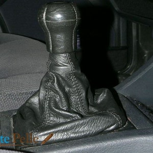 May include: Black leather gear shift knob with white stitching. The knob is installed in a car.
