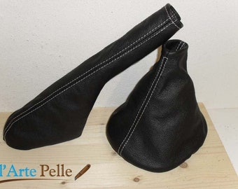 May include: Two black leather gear shift boots with white stitching. The boots are on a wooden surface.