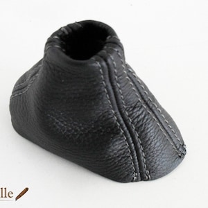 May include: Black leather gear shift boot with gray stitching.