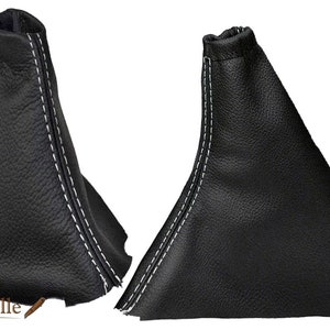May include: Two black leather gear shift boot covers with white stitching. The covers are made of genuine leather and have a classic look.