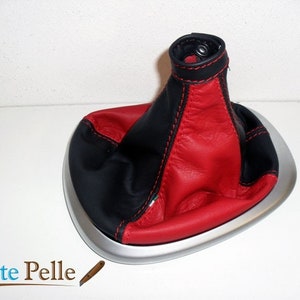 May include: A black and red leather gear shift boot with a silver base. The boot has red stitching and a black leather top.