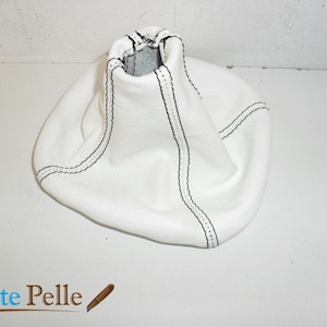 May include: White leather gear shift boot with black stitching.