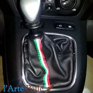 May include: A black leather gear shift boot with a red, white, and green stripe down the center. The boot is surrounded by a silver metal trim.