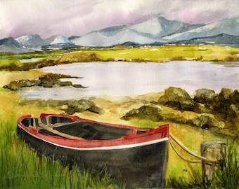 May include: A red and black wooden boat sits on a sandy shore with green grass and a body of water in the background. The water is calm and reflects the sky, which is a light blue with white clouds. In the distance, there are mountains with snow on the peaks.