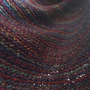 May include: A close-up of a textured fabric with a swirling pattern in shades of red, blue, and green.
