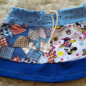 Könnte beinhalten: Ein blauer Patchwork-Rock mit Kordelzug. Der Rock hat eine blaue Basis, ein Patchwork-Design mit verschiedenen Mustern und einen oberen Bereich mit schwarzen Punkten. Ein Teil des Rocks hat einen Minnie Mouse-Druck.
