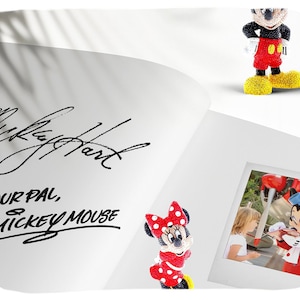 K&ouml;nnte beinhalten: Eine wei&szlig;e Seite mit einer schwarzen Unterschrift, die "Mickey Hart" und "Your Pal, Mickey Mouse" lautet. Auf der Seite befindet sich eine kleine rot-wei&szlig;e Minnie Mouse Figur. Ein Foto eines jungen M&auml;dchens, das Minnie Mouse trifft, befindet sich in einem Rahmen auf der Seite.
