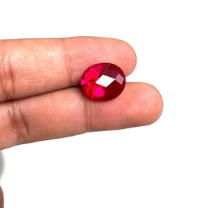 May include: A deep red oval-shaped gemstone with a faceted cut.
