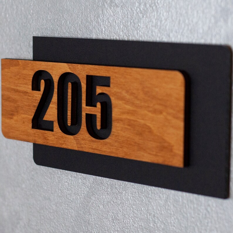 Puede incluir: Un letrero de n&uacute;mero de casa de madera con letras negras. El n&uacute;mero 205 se muestra en el letrero.