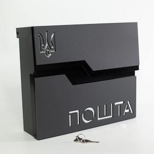 Könnte beinhalten: Ein schwarzer Metallbriefkasten mit dem ukrainischen Wappen und dem ausgeschnittenen Wort "ПОШТА". Der Briefkasten hat ein modernes Design und enthält einen Schlüsselsatz.
