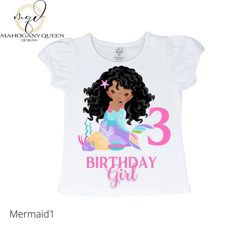 May include: White t-shirt with a pink number 3, the words "Birthday Girl" and a cartoon illustration of a mermaid with brown hair and a purple tail. The mermaid is holding a starfish.