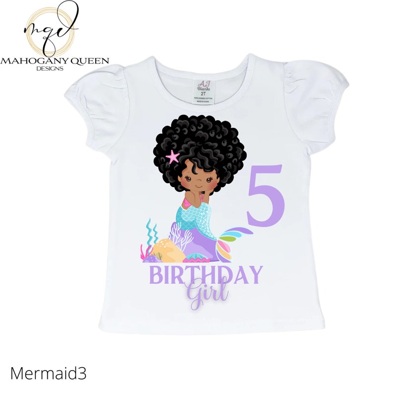May include: White t-shirt with a purple number 5, the words "birthday girl" and a cartoon illustration of a Black mermaid with a pink star in her hair.