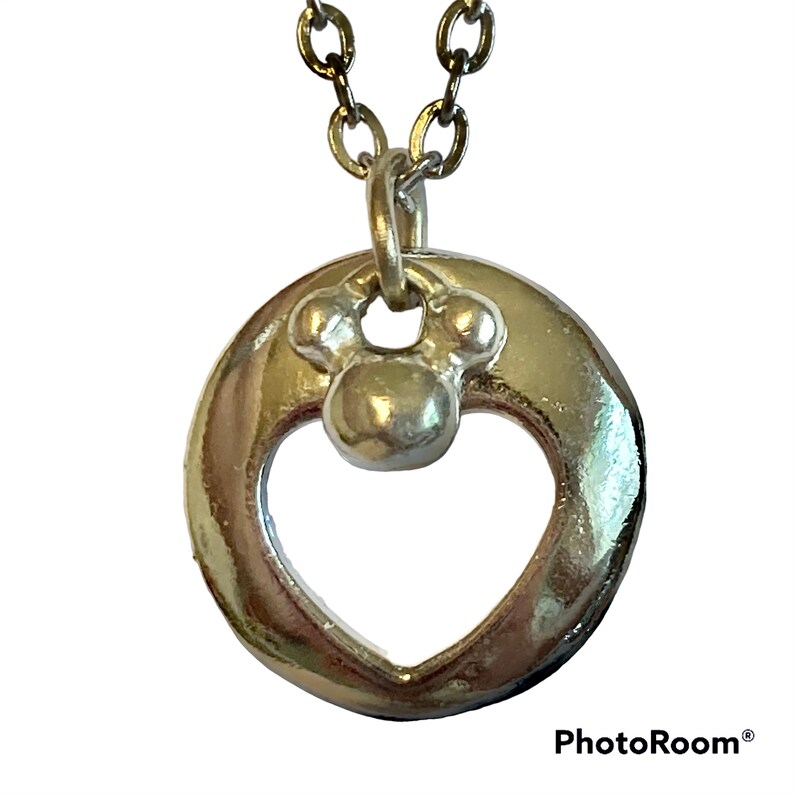 May include: Silver necklace with a heart-shaped pendant featuring a Mickey Mouse head charm.