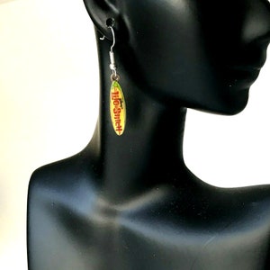 May include: A pair of silver dangle earrings with a yellow, red, and green surfboard charm. The charm has the text "Lilo & Stitch" on it.
