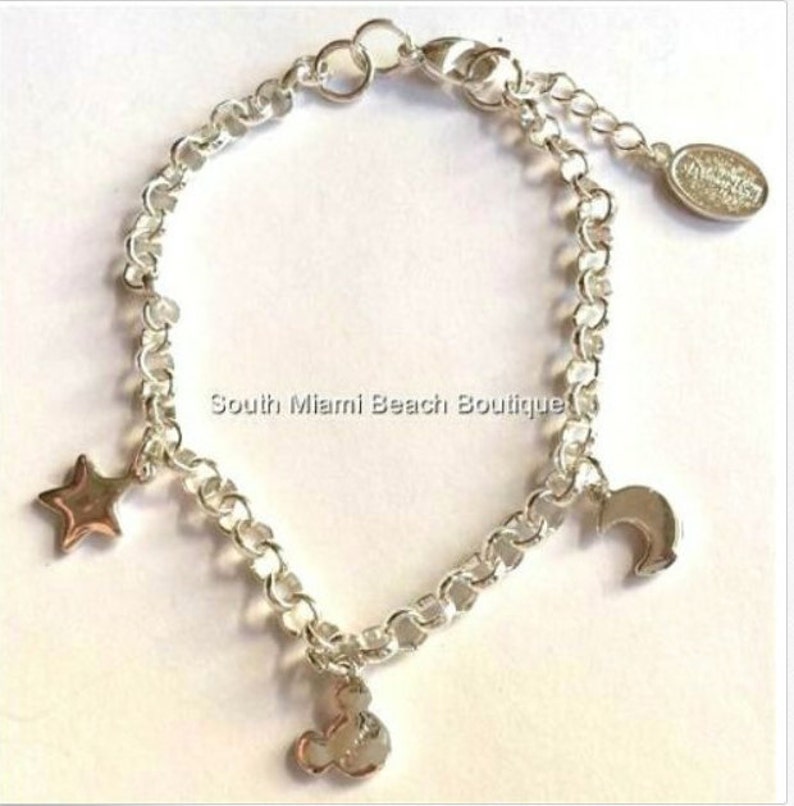 Puede incluir: Pulsera de plata con un dije de Mickey Mouse, un dije de estrella y un dije de media luna. La pulsera tiene un cierre de langosta.