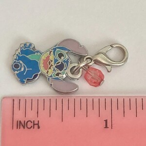 Puede incluir: Un charm plateado con un cierre de mosquet&oacute;n, con un dise&ntilde;o de personaje de dibujos animados colorido. El charm tiene detalles de esmalte azul, rosa y amarillo, con una peque&ntilde;a cuenta roja. El charm mide aproximadamente 2,5 cm de largo.