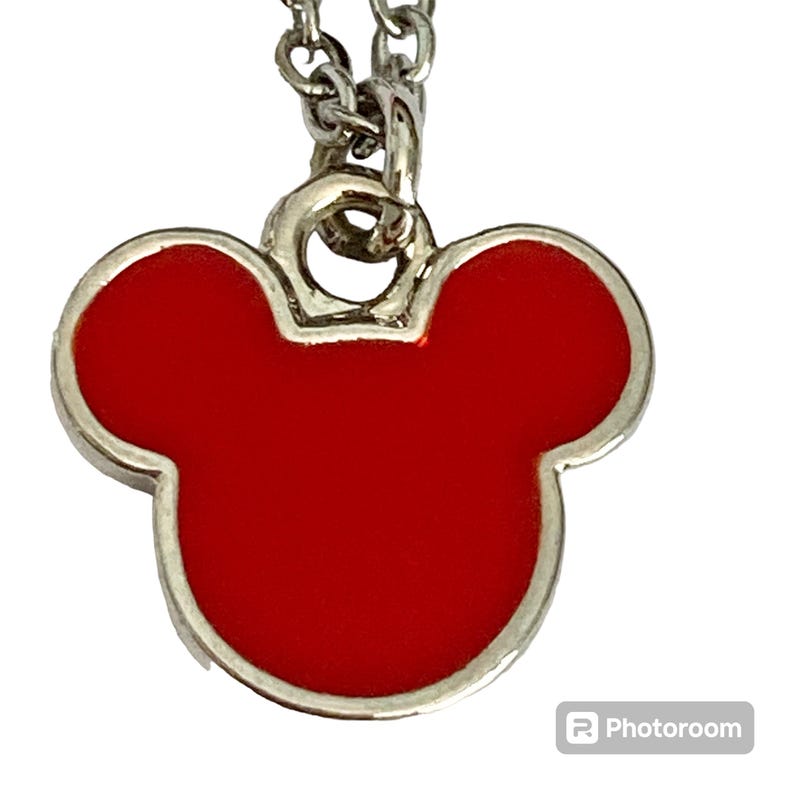K&ouml;nnte beinhalten: Eine silberne Kettenkette mit einem roten Mickey Mouse Kopf Anh&auml;nger.