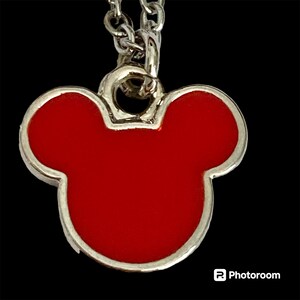 K&ouml;nnte beinhalten: Eine silberne Kettenkette mit einem roten Mickey Mouse Kopf Anh&auml;nger.