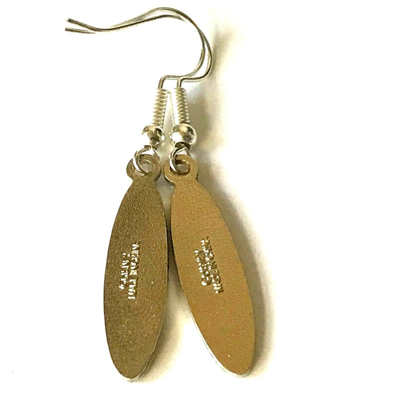 May include: A pair of silver earrings with oval-shaped charms. The charms are gold-colored and have text on the back. The text on the left charm reads "MADE IN ITALY" and the text on the right charm reads "ORIGINAL DESIGN".