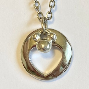 May include: Silver necklace with a heart-shaped pendant featuring a small paw print charm.