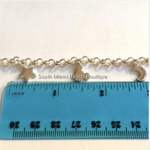 Puede incluir: Un brazalete de cadena de plata con dijes de estrella, luna y coraz&oacute;n. El brazalete se mide en una regla que muestra que mide poco m&aacute;s de 1 pulgada de largo.