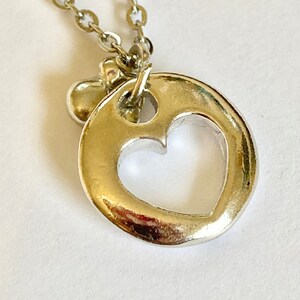 May include: A silver necklace with a heart-shaped pendant. The pendant has a cutout heart design.
