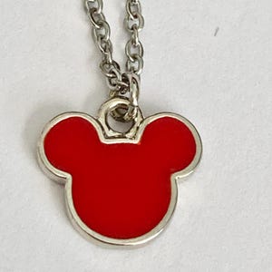 K&ouml;nnte beinhalten: Eine silberne Kettenkette mit einem roten Mickey-Maus-Kopf-Anh&auml;nger aus Emaille.