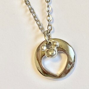 May include: Silver necklace with a heart-shaped pendant and a small paw print charm.