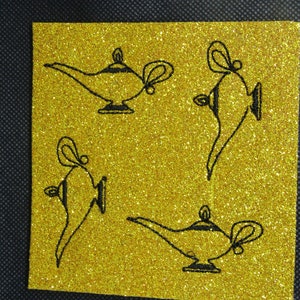 Puede incluir: Una superficie cuadrada dorada y brillante con cuatro dibujos lineales negros de lámparas de genio. Las lámparas están en diferentes orientaciones, cada una con un pico curvo, un asa y una base decorativa. El fondo es una tela oscura y texturizada.