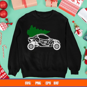 Puede incluir: Sudadera negra con una silueta blanca de un vehículo todoterreno Can-Am con un árbol de Navidad en la parte superior. El texto "Can-Am" es visible en el vehículo.
