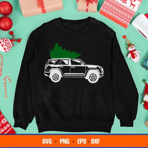 Puede incluir: Una sudadera negra con un diseño blanco de un coche con un árbol de Navidad en la parte superior. El diseño está en la parte delantera de la sudadera.