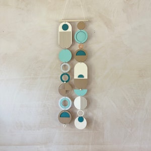 A handmade large wall hanging made of plywood and other materials. Measuring 80cm long by 22cm wide. Painted mainly in blue, green and yellow tones. Inspired by the colours you see at a beach.