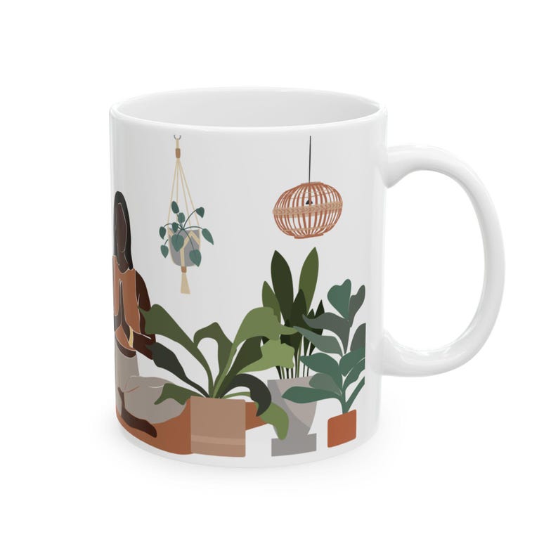 Pu&ograve; includere: Tazza in ceramica bianca con un'illustrazione colorata di una persona che medita circondata da piante e un lampadario sospeso. La tazza ha un manico arrotondato.