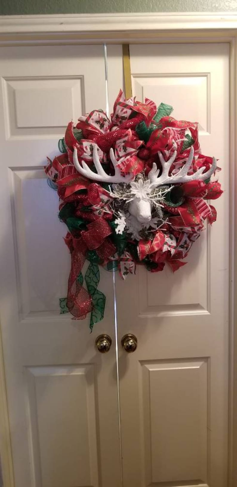 Large red and green wreath with a snow white deer in the center.