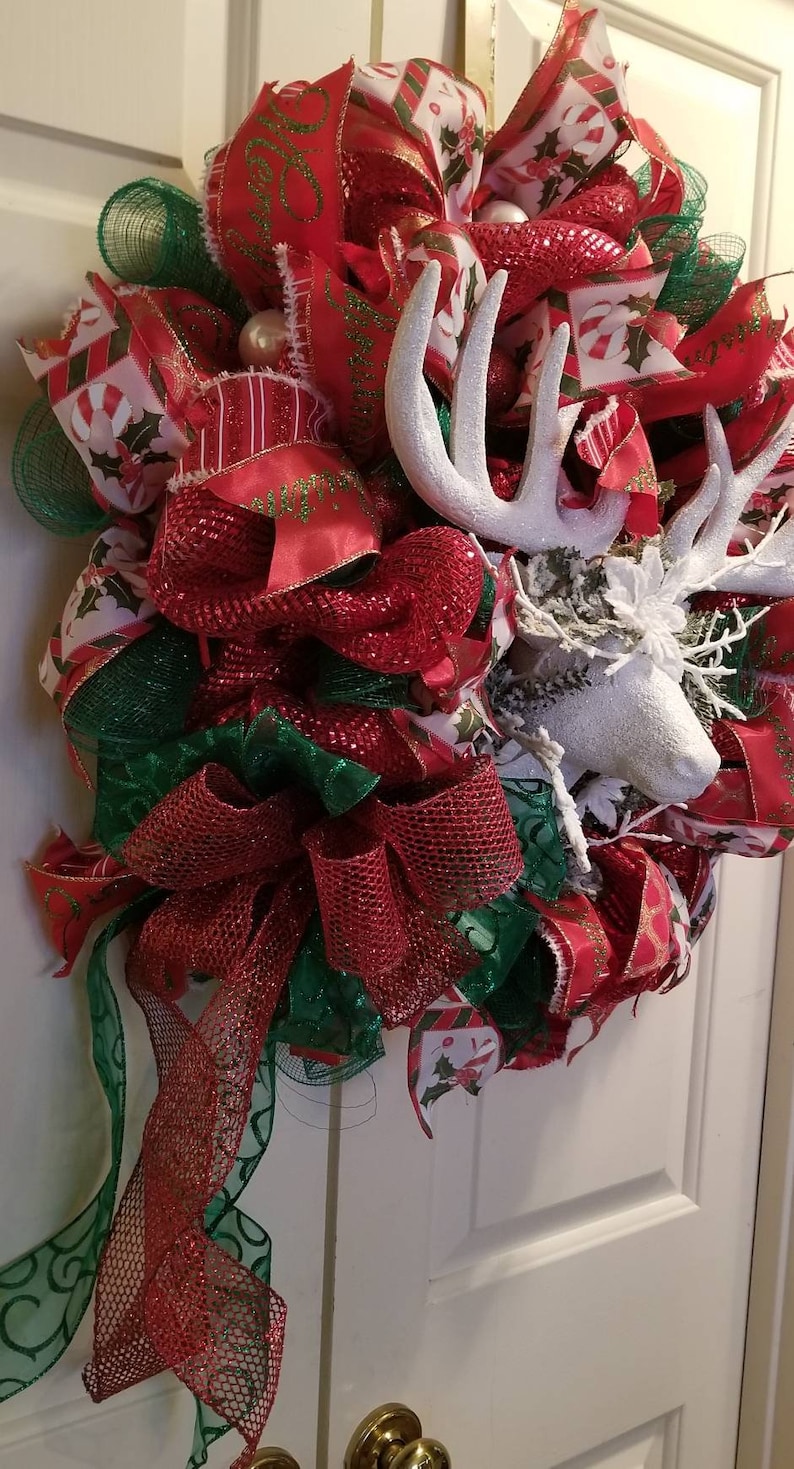 Large red and green wreath with a snow white deer in the center.